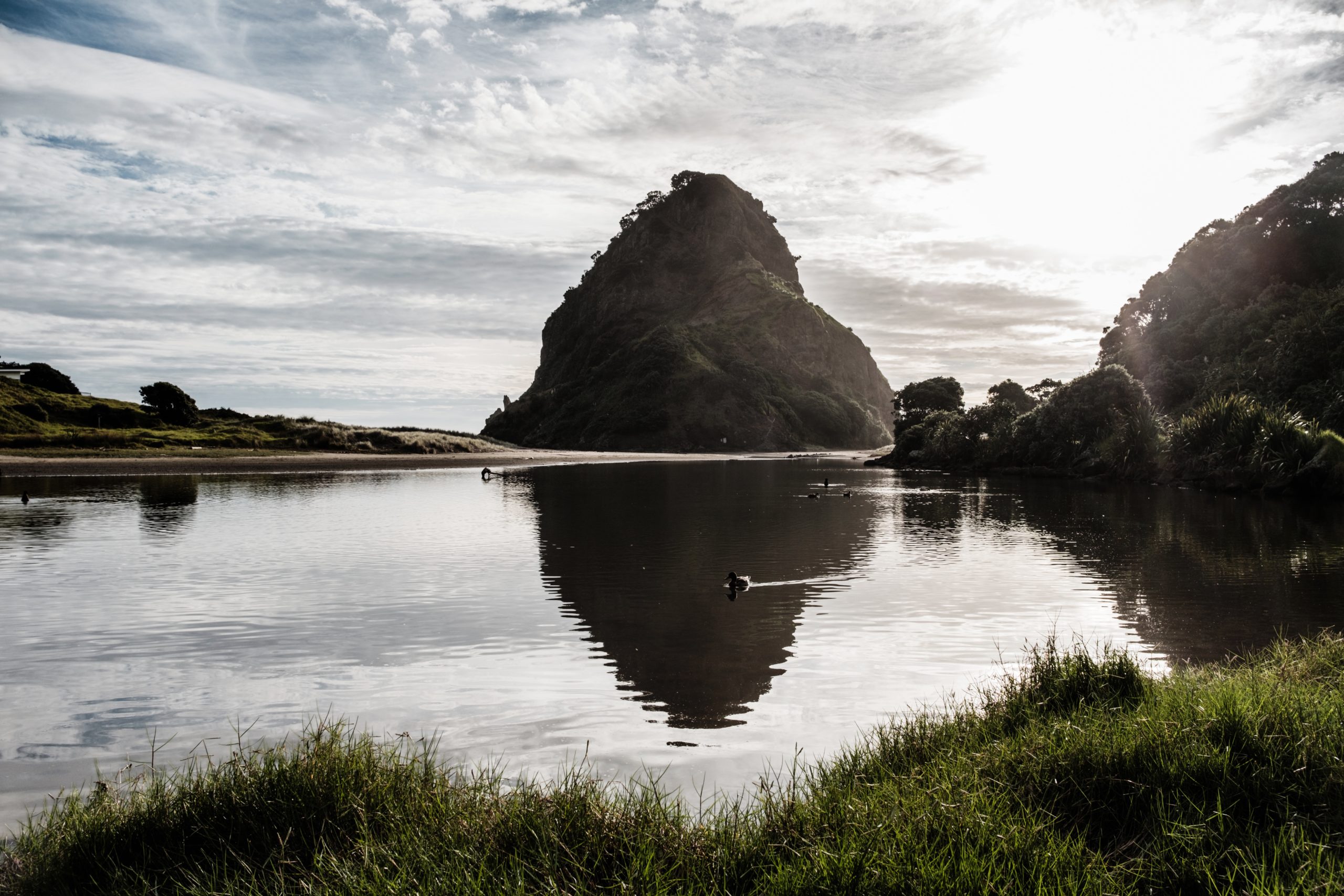 Le rocher de la plage de Piha et son reflet dans le lagon